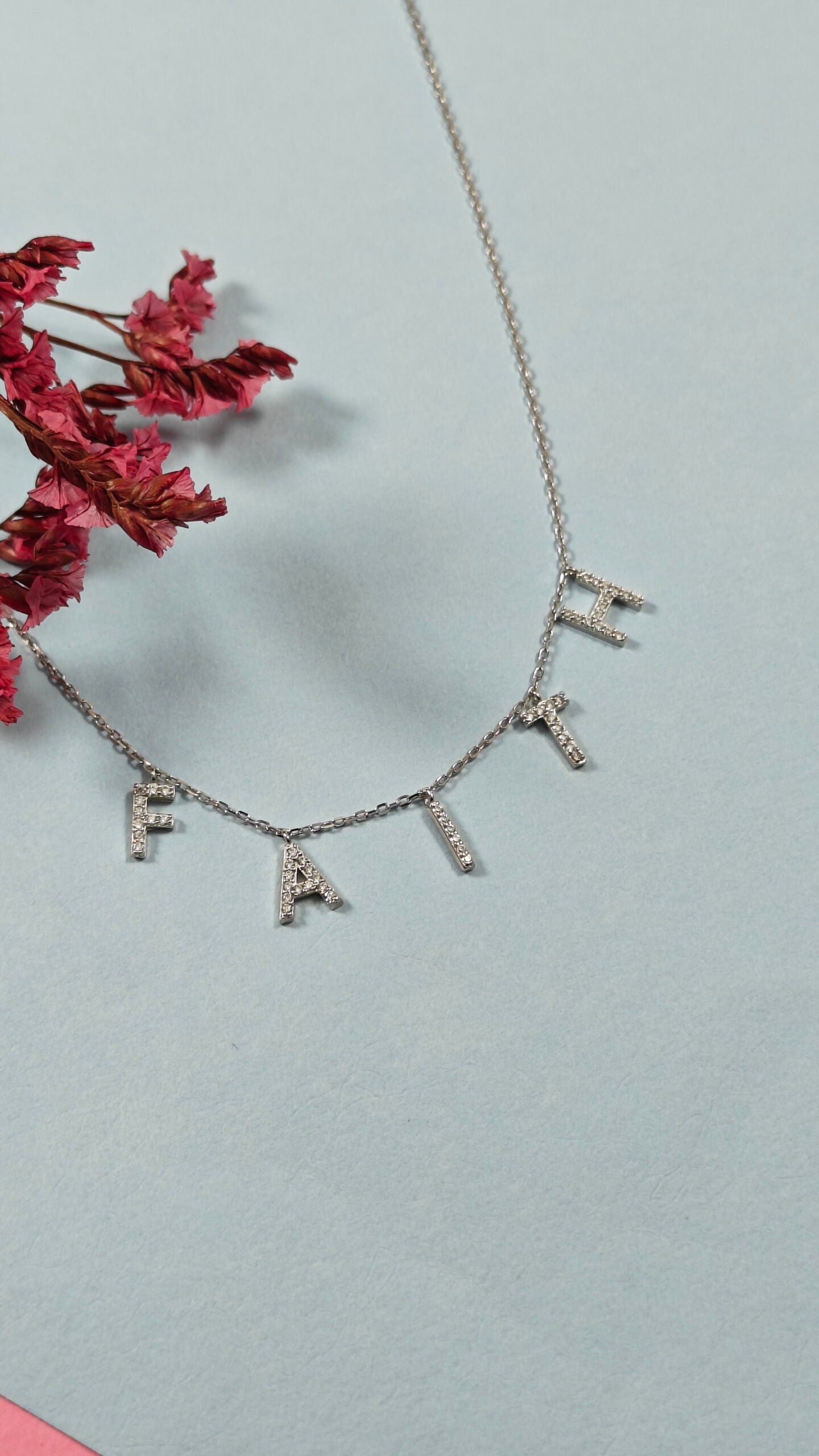 Necklace with diamond-studded letters on a light blue background